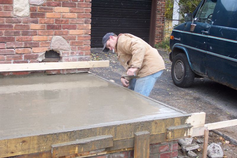 The bricklayer smooths the edges of the form.