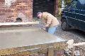 The bricklayer smooths the edges of the form.